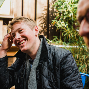 Man laughing and enjoying conversation at an outdoor café during a food tour stop in London.