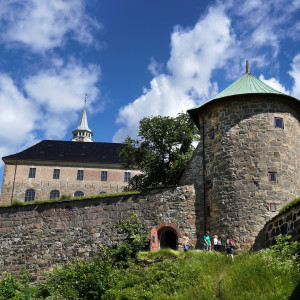 Stone walls and towers of medieval Akershus Fortress in Oslo against a blue sky with scattered clouds