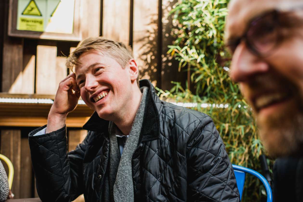 Man laughing and enjoying conversation at an outdoor café during a food tour stop in London.