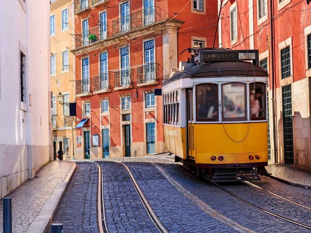 Things to do in Lisbon: Narrow road of Lisbon with a yellow tram