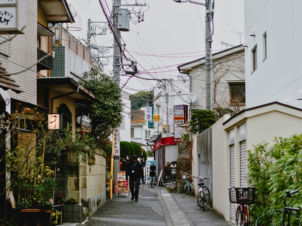 A man walks away from the camera on a neighborhood street in Tokyo