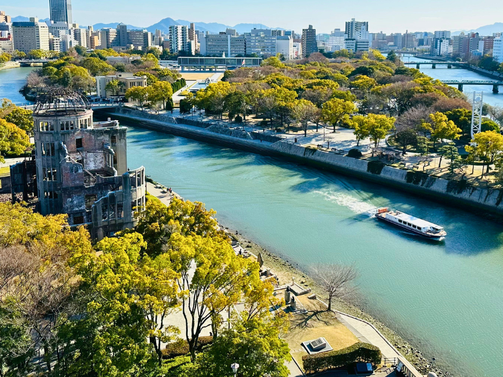 A bird's eye view of Hiroshima, with the Atomic Bomb Dome and city skyline in the background