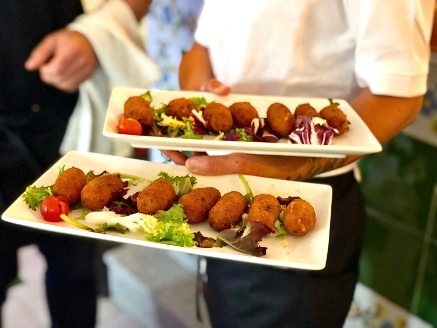 A waiter carrying croquettes