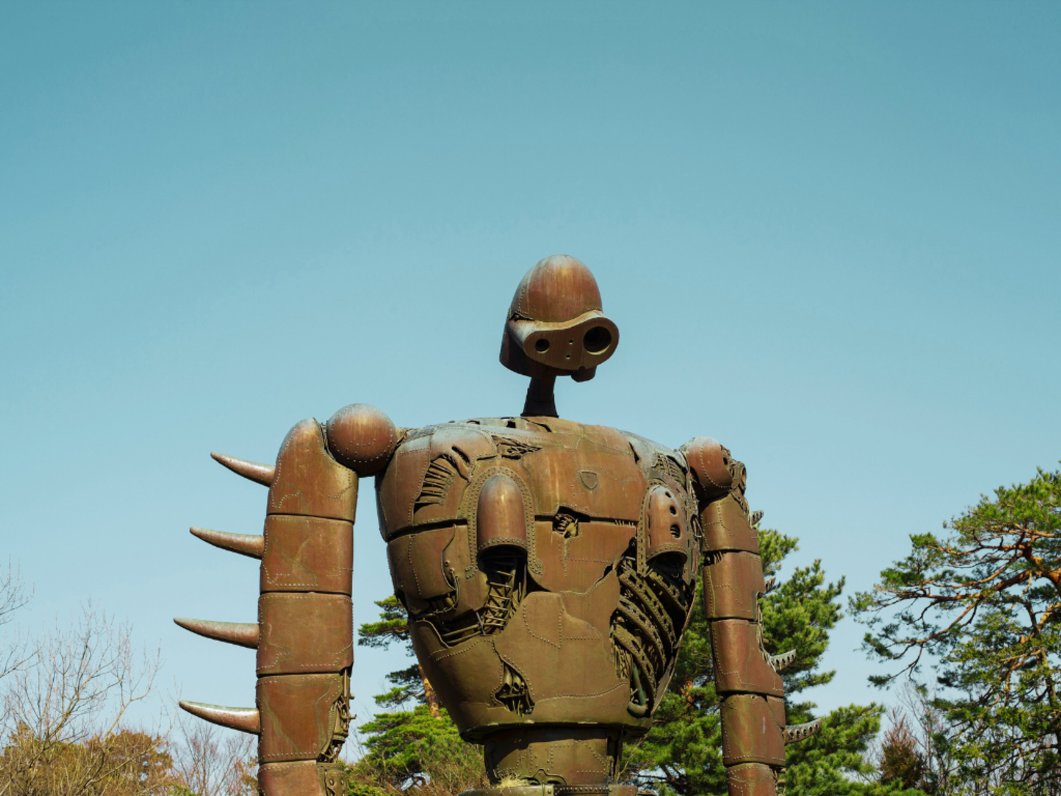 A metal sculpture of a Laputian robot sits against a blue cloudless sky